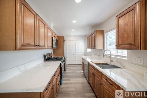 A kitchen with wooden cabinets and a marble countertop.