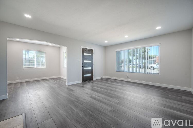 A spacious room with wooden flooring and a large window.