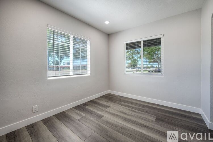 A room with two windows and wooden flooring.