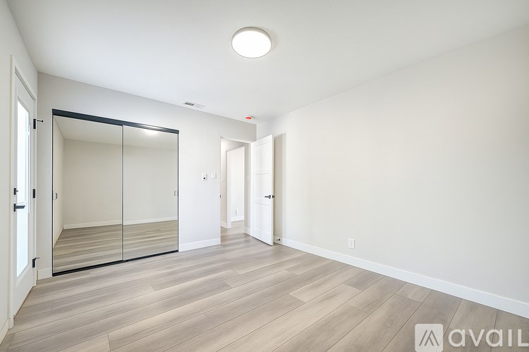 A spacious room with a sliding door and wooden flooring.