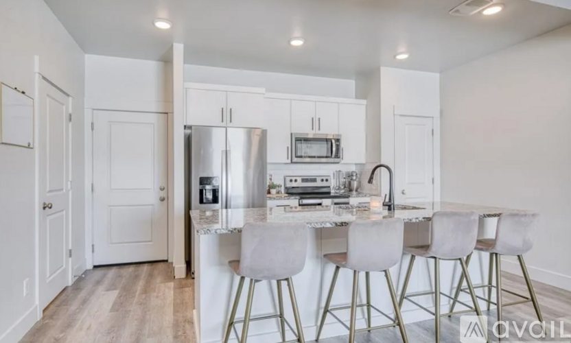 A kitchen with white cabinets and a white island with four barstools.