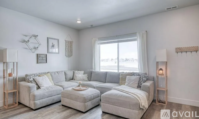 A living room with a grey sofa set and a large window.