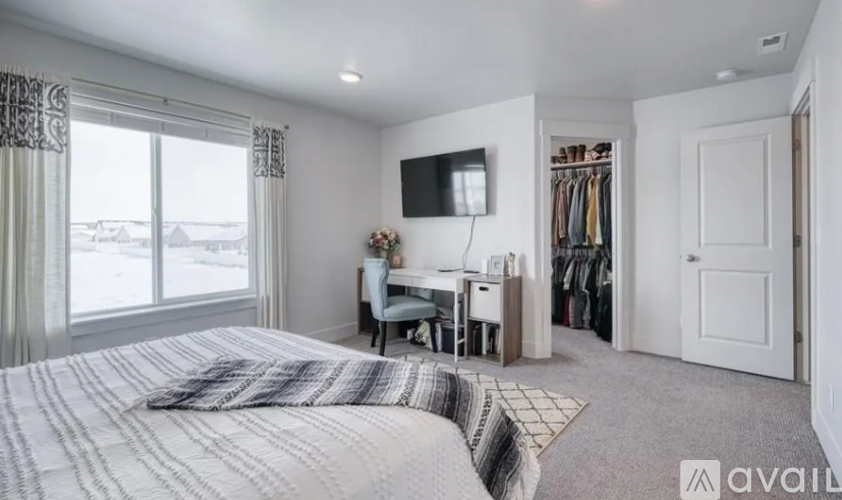 A bedroom with a large bed and a television on the wall.