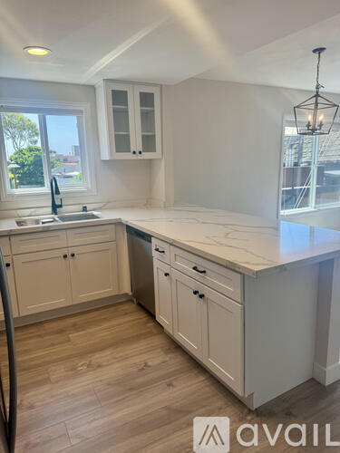 A kitchen with white cabinets and a wooden floor.