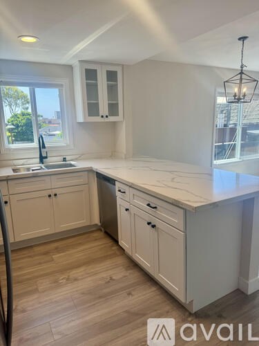 A kitchen with white cabinets and a wooden floor.