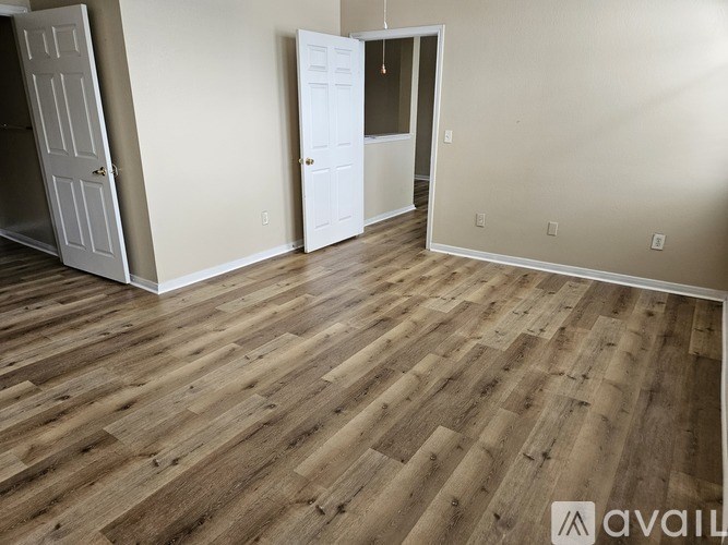 A room with wooden flooring and two white doors.