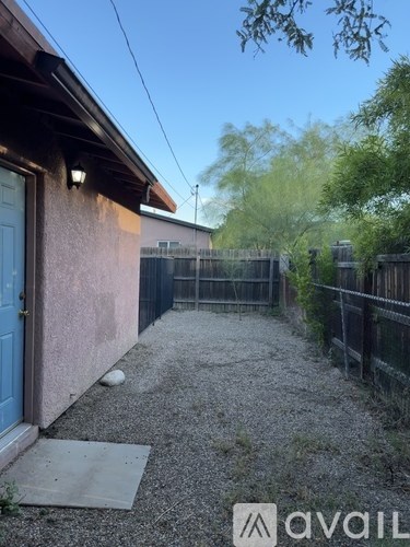A backyard with a blue door and a gravel path.