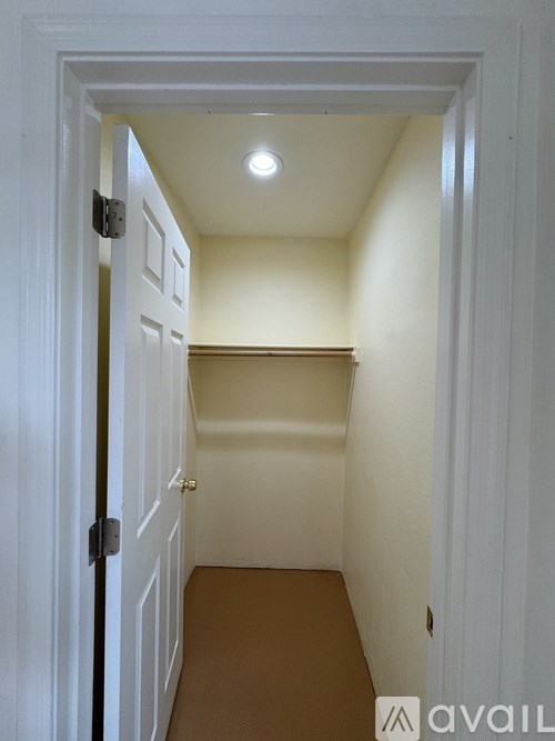 A white door with a black handle is open to a hallway.