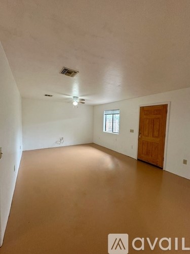 A room with a brown floor and a wooden door.