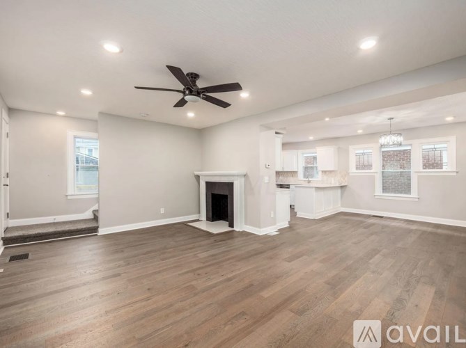 A spacious living room with a fireplace and a ceiling fan.