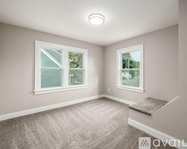 A room with a carpeted floor and two windows.