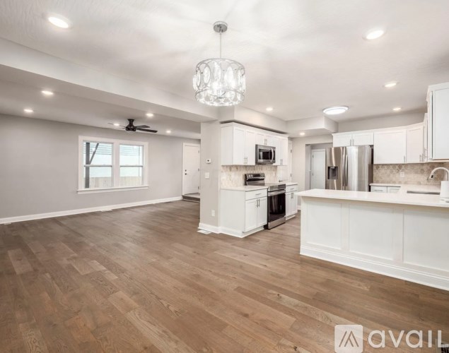 A spacious kitchen with white cabinets and a wooden floor.