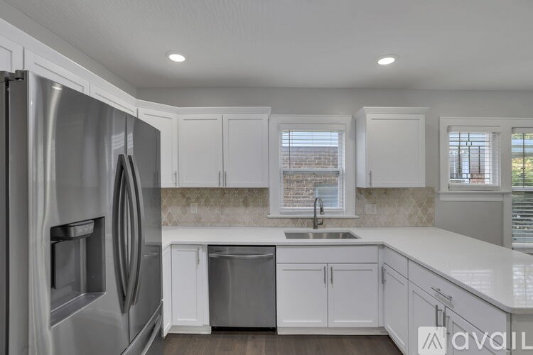 A modern kitchen with white cabinets and a stainless steel refrigerator.