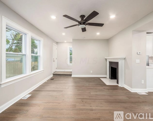 A spacious living room with a fireplace and a ceiling fan.