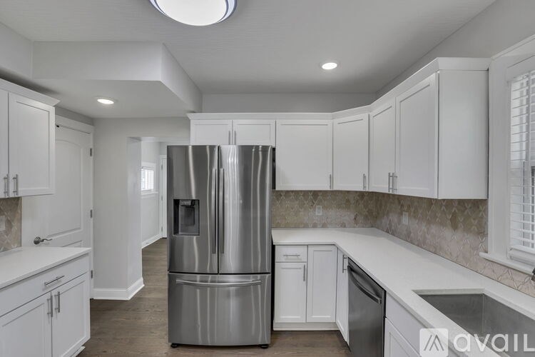 A kitchen with white cabinets and a stainless steel refrigerator.