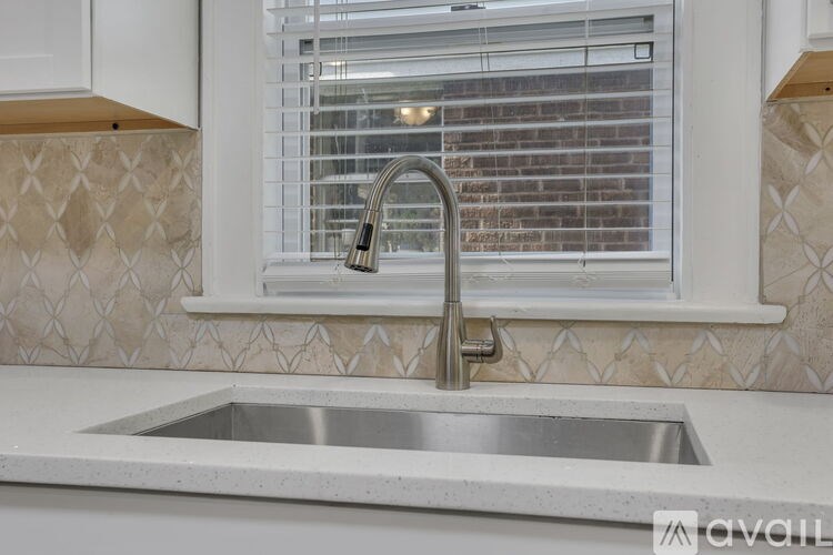 A kitchen sink with a silver faucet and a window above it.