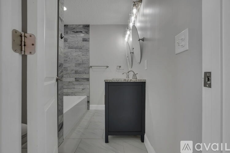 A bathroom with a marble wall and a black cabinet.