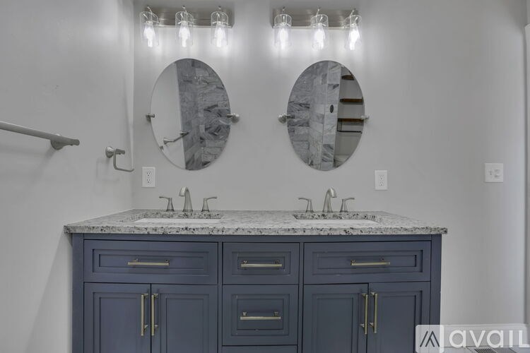 A bathroom vanity with a marble countertop and two round mirrors above it.