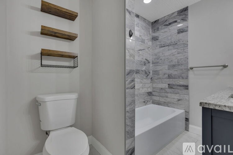 A white toilet sits next to a marble tiled shower.