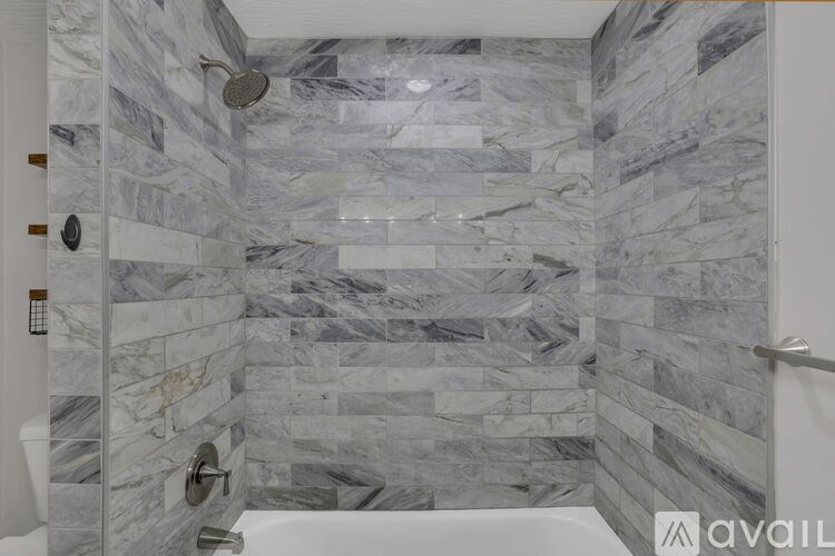 A shower area with a marble tile wall.