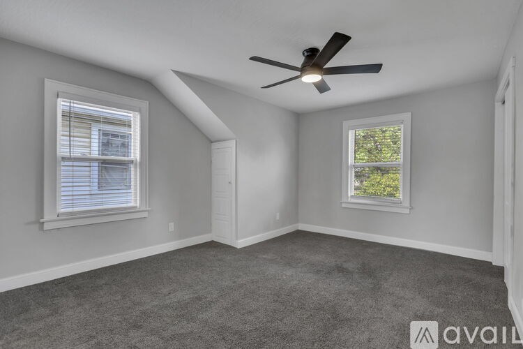 A room with a ceiling fan and two windows.