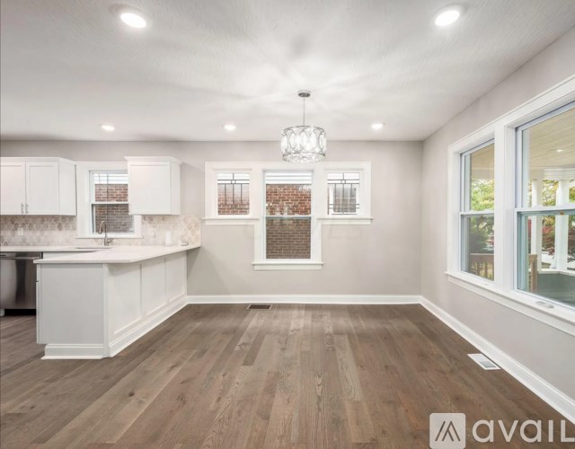 A well-lit kitchen with wooden floors and white cabinets.