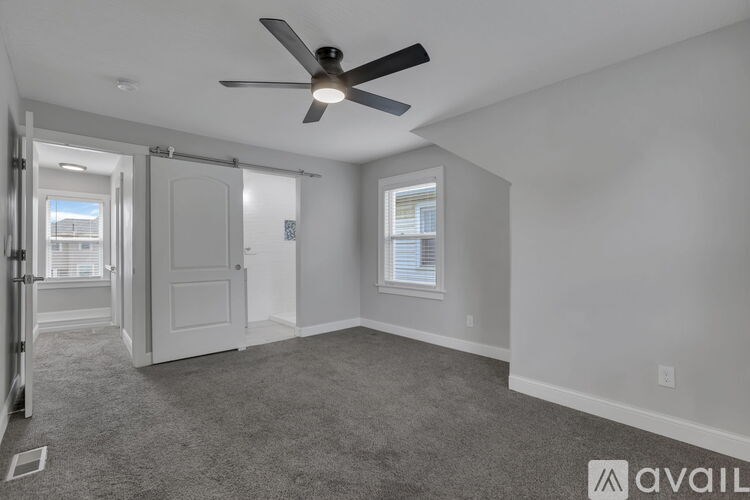 A spacious room with a ceiling fan and carpeted floor.