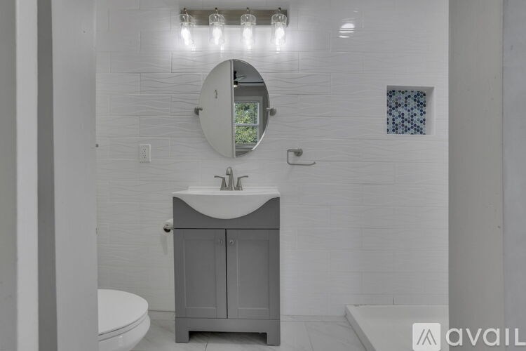 A bathroom with a white sink and a round mirror.
