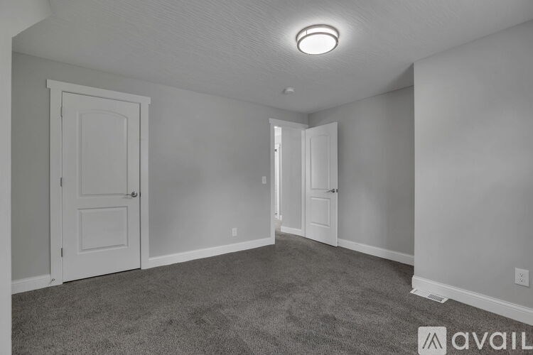 A spacious room with a carpeted floor and two doors.