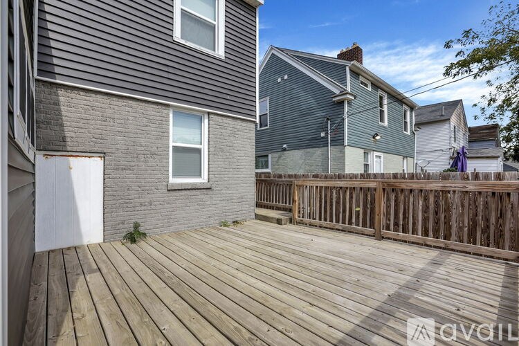 A wooden deck in front of a grey house with a white door.
