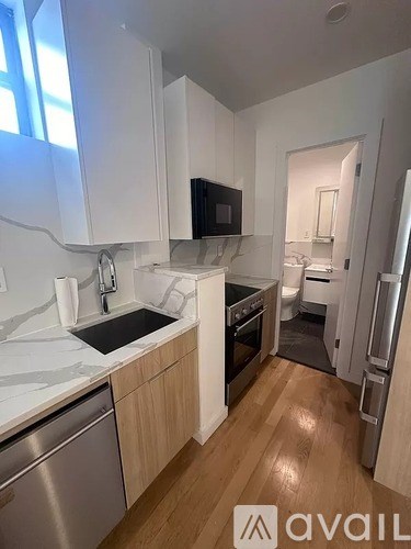 A kitchen with white cabinets and a wooden floor.
