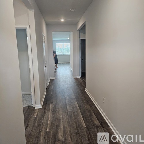 A hallway with wood flooring and white walls.