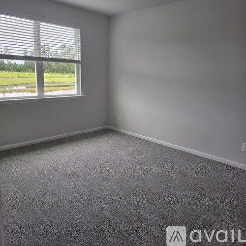 A room with a window overlooking a green field.