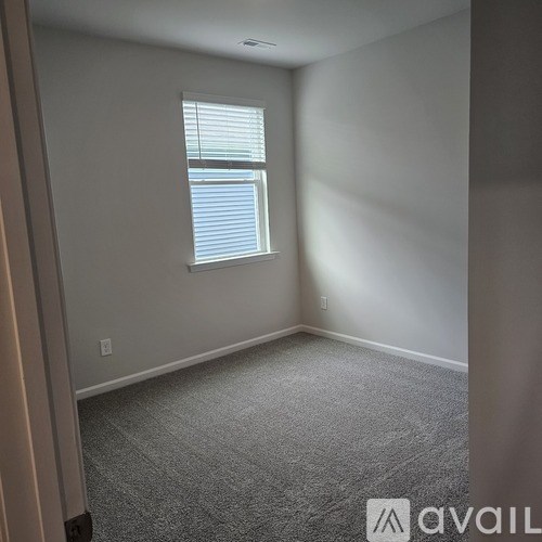 A room with a carpeted floor and a window with blinds.