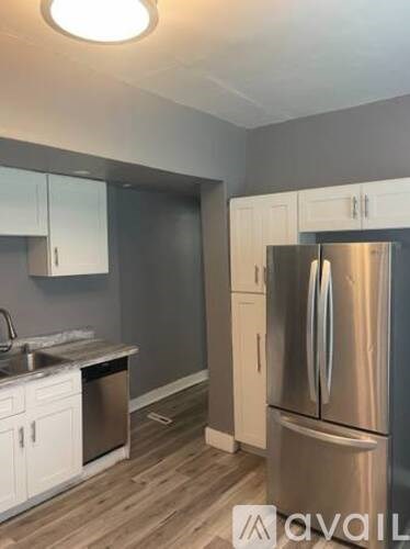 A modern kitchen with a stainless steel refrigerator and white cabinets.
