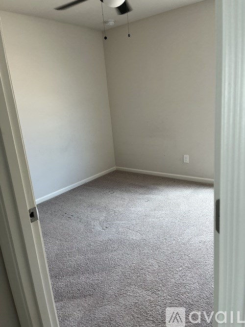 A room with a carpeted floor and a ceiling fan.
