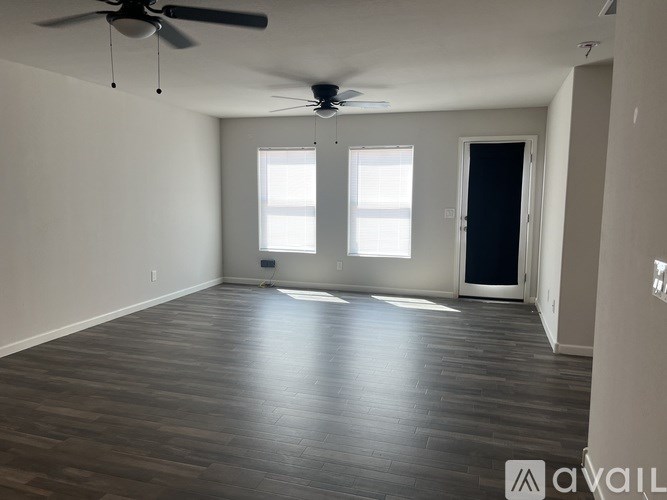 A spacious room with a ceiling fan and wooden flooring.