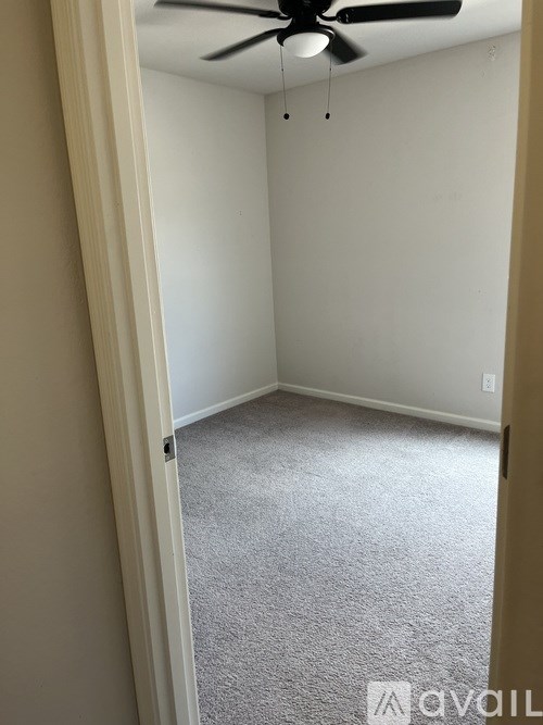 A room with a carpeted floor and a ceiling fan.