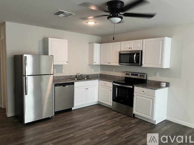 A kitchen with a refrigerator, microwave, oven, and cabinets.