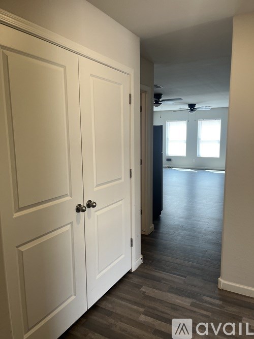 A hallway with a white door and a fan on the ceiling.