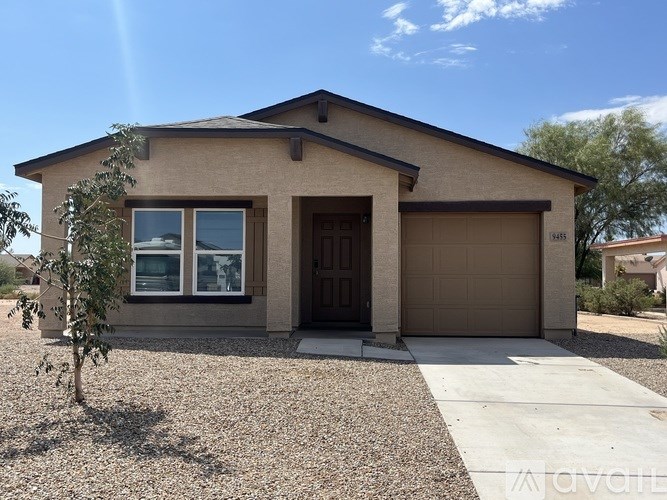 A house with a brown garage door and a brown tree in front of it.