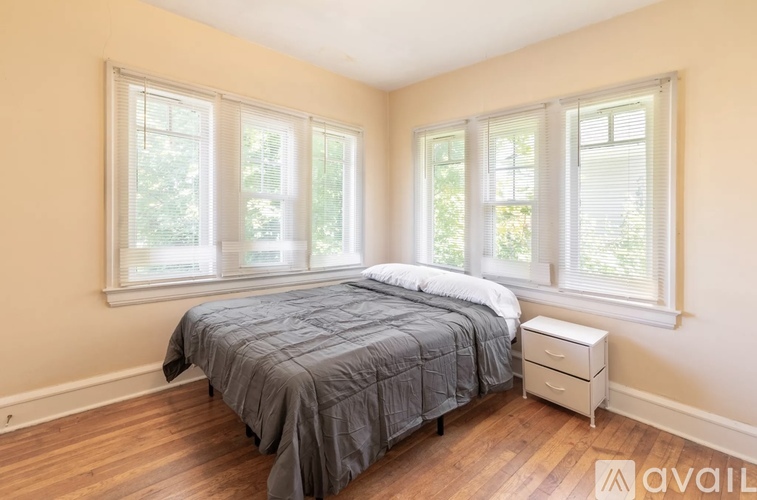 A bedroom with a bed, nightstand, and windows.