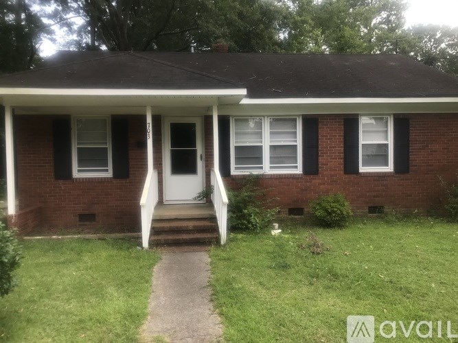A brick house with a white door and windows.