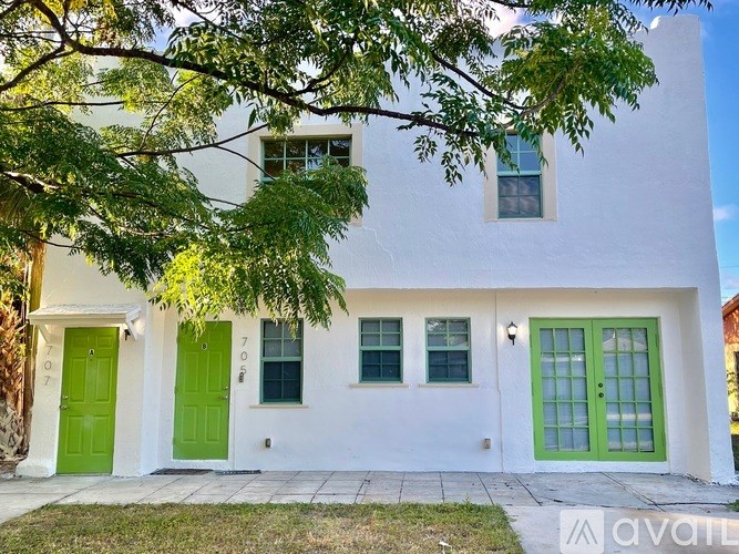 A white house with green doors and windows is for sale.