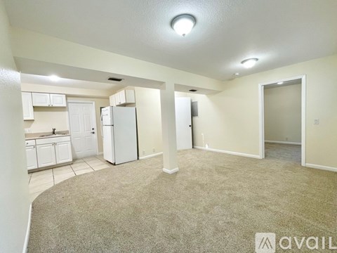 A spacious living room with a kitchen area in the background.