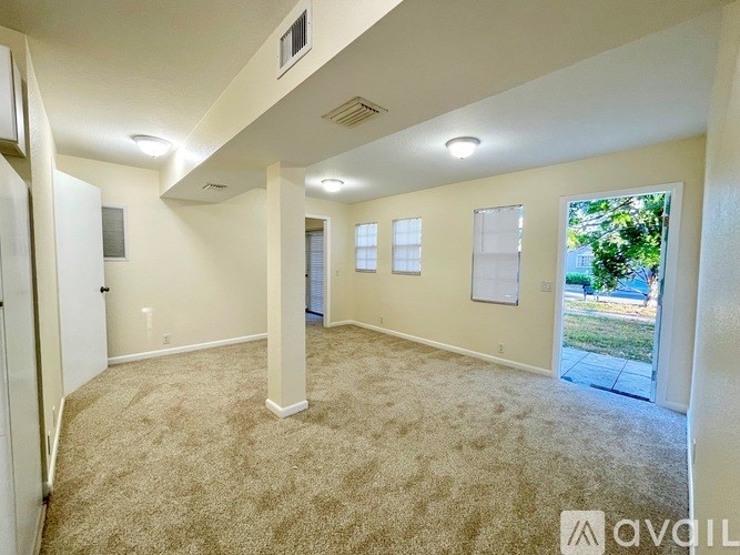 A living room with beige carpeting and white walls.