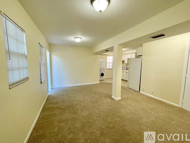 A spacious living room with beige carpeting and white walls.