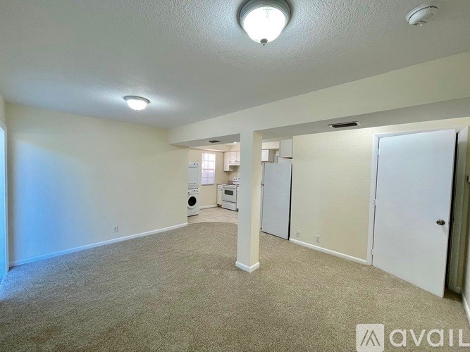 A spacious living room with a washer and dryer in the corner.