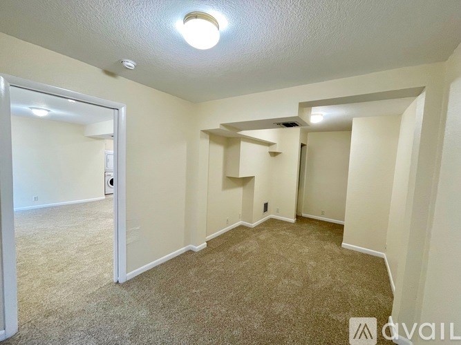 A room with carpeted floor and a ceiling fan.