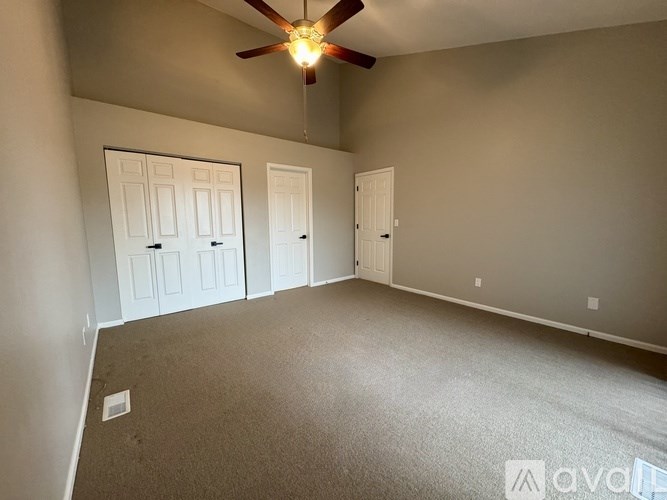 A room with a ceiling fan and carpeted floor.